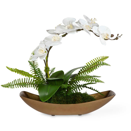A Graceful, Flowing White Orchid Seems To Float Over A Bed Of Naturally Preserved Moss In A Textured Cast Aluminum Antique Brass Boat.